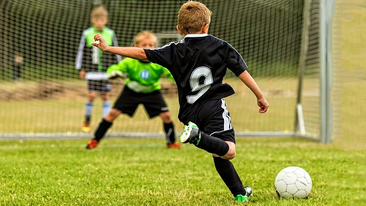 Young boy in black shirt shooting soccer ball