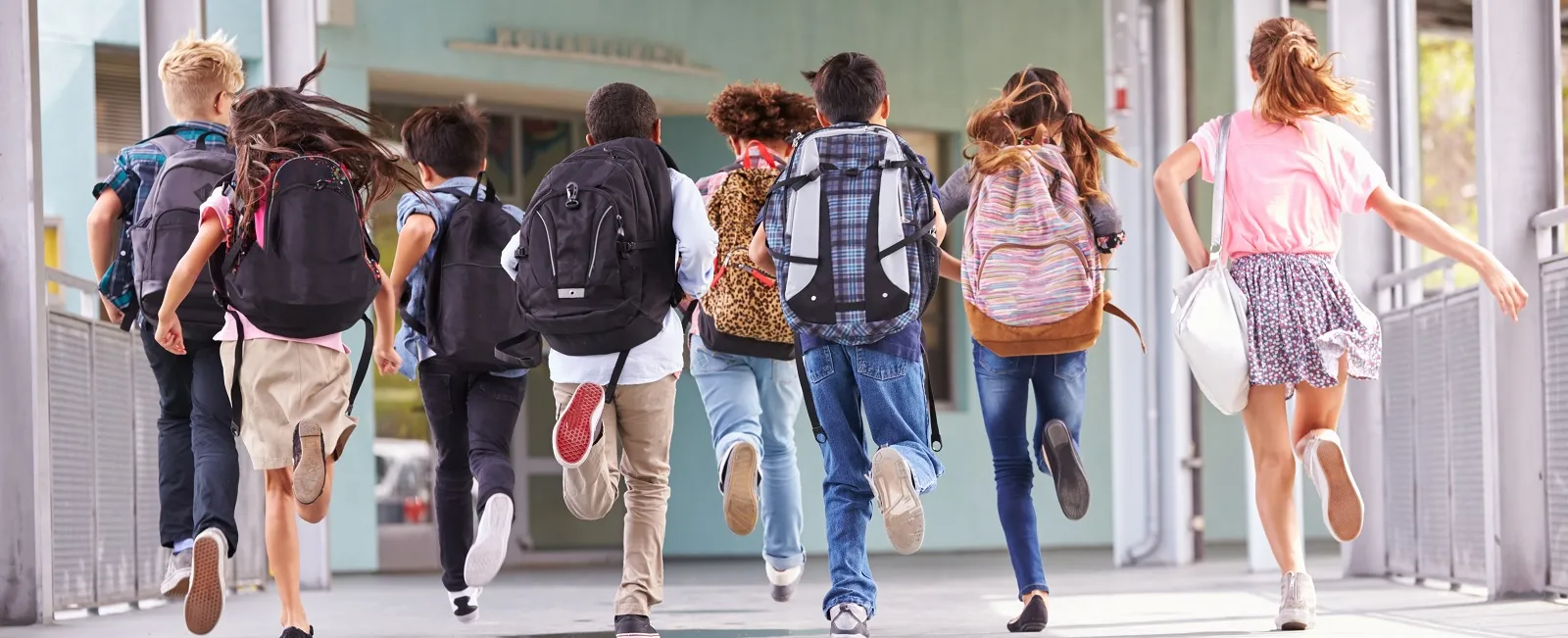 School age kids with backpacks running