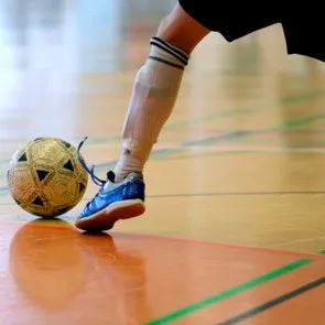 Close up of someone drilling an indoor soccer ball on a gym floor
