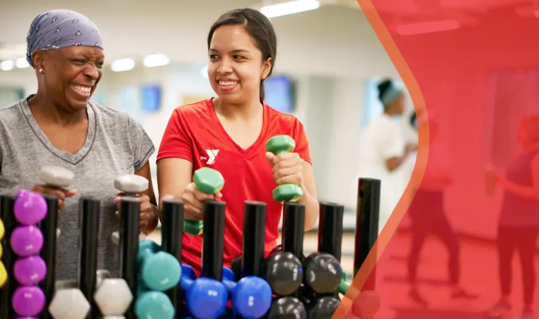 Two women standing at a weight rack smiling.